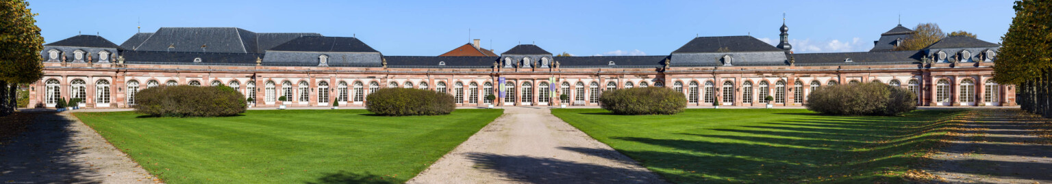 Schloss und Schlossgarten Schwetzingen - Garten - Nördlicher Zirkelbau - Von Südwest - Blick auf den gesamten nördlichen Zirkelbau (Gesamter Bau: Länge Bogen ca. 175 Meter, Breite zwischen ca. 11 und 18 Meter, 51 Achsen, 5 Pavillons, 4 Zwischenbauten; Architekt: Alessandro Alessandro Galli da Bibiena (1686-1748), Bauleitung: zuerst Guillaume d’Hauberat (1680–1749), dann Nicolas de Pigage (1723-1796); Bauzeit: 1748-1750) (aufgenommen im Oktober 2024, am frühen Nachmittag)