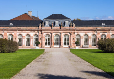 Schloss und Schlossgarten Schwetzingen - Garten - Nördlicher Zirkelbau - Von Südwest - Blick auf den zentralen Teil des nördlichen Zirkelbaus (Gesamter Bau: Länge Bogen ca. 175 Meter, Breite zwischen ca. 11 und 18 Meter, 51 Achsen, 5 Pavillons, 4 Zwischenbauten; Architekt: Alessandro Alessandro Galli da Bibiena (1686-1748), Bauleitung: zuerst Guillaume d’Hauberat (1680–1749), dann Nicolas de Pigage (1723-1796); Bauzeit: 1748-1750) (aufgenommen im Oktober 2024, am frühen Nachmittag)