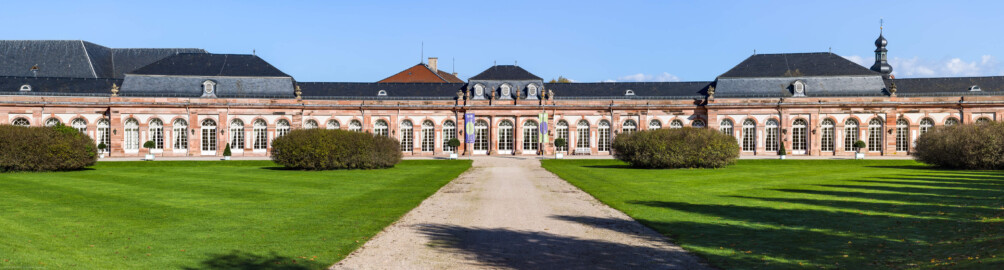 Schloss und Schlossgarten Schwetzingen - Garten - Nördlicher Zirkelbau - Von Südwest - Blick auf den zentralen Teil des nördlichen Zirkelbaus (Gesamter Bau: Länge Bogen ca. 175 Meter, Breite zwischen ca. 11 und 18 Meter, 51 Achsen, 5 Pavillons, 4 Zwischenbauten; Architekt: Alessandro Alessandro Galli da Bibiena (1686-1748), Bauleitung: zuerst Guillaume d’Hauberat (1680–1749), dann Nicolas de Pigage (1723-1796); Bauzeit: 1748-1750) (aufgenommen im Oktober 2024, am frühen Nachmittag)