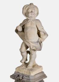 Schloss und Schlossgarten Schwetzingen - Garten - Nördlicher Zirkelbau - Westlicher Pavillon / Foyer des Schlosstheaters - Von innen - Südwand - 3. Zwergenfigur / Putto von Osten - Blick auf eine der fünf Zwergenfiguren / Putti (Kopie einer Zwergenfigur aus Schloss Veitshöchheim, wohl 18. Jh.; 1937 im Foyer aufgestellt) (Gesamter Bau: Länge Bogen ca. 175 Meter, Breite zwischen ca. 11 und 18 Meter, 51 Achsen, 5 Pavillons, 4 Zwischenbauten; Architekt: Alessandro Alessandro Galli da Bibiena (1686-1748), Bauleitung: zuerst Guillaume d’Hauberat (1680–1749), dann Nicolas de Pigage (1723-1796); Bauzeit: 1748-1750) (aufgenommen im Oktober 2024, am Nachmittag)