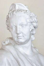 Schloss und Schlossgarten Schwetzingen - Garten - Nördlicher Zirkelbau - Westlicher Pavillon / Foyer des Schlosstheaters - Von innen - Nordwand, Ostseite - Standbild Kurfürstin Elisabeth Auguste - Ausschnitt aus dem Standbild der Kurfürstin Elisabeth Auguste von Pfalz-Sulzbach (1721-1794), mit langem Untergewand, hermelinbesetztem Mantel, über der Stirn ein Diadem, in der rechten Hand ein Lorbeerzweig, hinten rechts Rüstungsgegenstände (Brustpanzer und Fascienbündel), linker Fuß auf einem Schild, links ein Knabe mit dem Kurhut in Händen - Kopie, Original im Schloss Mannheim, im Rittersaal, in Ecknische (Zum Original: Bildhauer Peter Anton von Verschaffelt (1710-1793), Datierung 1758-60; Material weißer Marmor, Höhe ca. 245 cm) (Gesamter Bau: Länge Bogen ca. 175 Meter, Breite zwischen ca. 11 und 18 Meter, 51 Achsen, 5 Pavillons, 4 Zwischenbauten; Architekt: Alessandro Alessandro Galli da Bibiena (1686-1748), Bauleitung: zuerst Guillaume d’Hauberat (1680–1749), dann Nicolas de Pigage (1723-1796); Bauzeit: 1748-1750) (aufgenommen im November 2024, am frühen Nachmittag) Schloss und Schlossgarten Schwetzingen - Garten - Nördlicher Zirkelbau - Westlicher Pavillon / Foyer des Schlosstheaters - Von innen - Nordwand, Ostseite - Standbild Kurfürstin Elisabeth Auguste - Ausschnitt aus dem Standbild der Kurfürstin Elisabeth Auguste von Pfalz-Sulzbach (1721-1794), mit langem Untergewand, hermelinbesetztem Mantel, über der Stirn ein Diadem, in der rechten Hand ein Lorbeerzweig, hinten rechts Rüstungsgegenstände (Brustpanzer und Fascienbündel), linker Fuß auf einem Schild, links ein Knabe mit dem Kurhut in Händen - Kopie, Original im Schloss Mannheim, im Rittersaal, in Ecknische (Zum Original: Bildhauer Peter Anton von Verschaffelt (1710-1793), Datierung 1758-60; Material weißer Marmor, Höhe ca. 245 cm) (Gesamter Bau: Länge Bogen ca. 175 Meter, Breite zwischen ca. 11 und 18 Meter, 51 Achsen, 5 Pavillons, 4 Zwischenbauten; Architekt: Alessandro Alessandro Galli da Bibiena (1686-1748), Bauleitung: zuerst Guillaume d’Hauberat (1680–1749), dann Nicolas de Pigage (1723-1796); Bauzeit: 1748-1750) (aufgenommen im November 2024, am frühen Nachmittag)