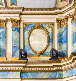 Schloss und Schlossgarten Schwetzingen - Garten - Schlosstheater - Von innen - Proszenium, Südseite - Blick auf den oberen Teil der korinthischen Pilasterordnung (in Höhe des Rangs); in der Mitte ein Medaillon in einem rechteckigen Rahmen (Medaillons ursprünglich mit figürlichen Darstellungen: "zwei kämpfende Faune und einen drachentötenden Helden"); die Kapitelle sind vergoldet, die Bemalung der Pilaster imitieren malachitfarbenen Stuckmarmor (Gesamter Bau: Länge x Breite: ca. 62 x 35 Meter; Architekt: Nicolas de Pigage (1723-1796); Bauzeit: 1752-1753, Erweiterung 1762, Sanierung: 1937, Renovierung: 1952, Generalsanierung / Umbau 1971-1974, Restaurierung: 1999-2005) (aufgenommen im Dezember 2024, um die Mittagszeit) Schloss und Schlossgarten Schwetzingen - Garten - Schlosstheater - Von innen - Proszenium, Südseite - Blick auf den oberen Teil der korinthischen Pilasterordnung (in Höhe des Rangs); in der Mitte ein Medaillon in einem rechteckigen Rahmen (Medaillons ursprünglich mit figürlichen Darstellungen: "zwei kämpfende Faune und einen drachentötenden Helden"); die Kapitelle sind vergoldet, die Bemalung der Pilaster imitieren malachitfarbenen Stuckmarmor (Gesamter Bau: Länge x Breite: ca. 62 x 35 Meter; Architekt: Nicolas de Pigage (1723-1796); Bauzeit: 1752-1753, Erweiterung 1762, Sanierung: 1937, Renovierung: 1952, Generalsanierung / Umbau 1971-1974, Restaurierung: 1999-2005) (aufgenommen im Dezember 2024, um die Mittagszeit)