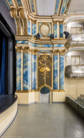 Schloss und Schlossgarten Schwetzingen - Garten - Schlosstheater - Von innen - Proszenium, Nordseite - Von Süden - Blick von der Südseite des Proszeniums auf die Nordseite; der Orchestergraben ist auf halber Höhe angehoben; im unteren Teil der Nordseite (vom Parkett bis zum Rang) die komposite Pilasterordnung; in der Mitte die Trompeterloge mit Musikinstrumenten (Trompeten, ein Paar Pauken, Tamburin, Schalmei, Panflöte), einer Krone und einem Degen auf einem Gitterwerk sowie auf Girlanden, einem verschlungenen Band und weiteren Verzierungen, unten die Tür zum Orchestergraben; im oberen Teil der Nordseite (Rang bis zur Decke) die korinthische Pilasterordnung; links oben der Architravbalken mit Volutenkonsolen (Gesamter Bau: Länge x Breite: ca. 62 x 35 Meter; Architekt: Nicolas de Pigage (1723-1796); Bauzeit: 1752-1753, Erweiterung 1762, Sanierung: 1937, Renovierung: 1952, Generalsanierung / Umbau 1971-1974, Restaurierung: 1999-2005) (aufgenommen im Dezember 2024, am frühen Nachmittag) Schloss und Schlossgarten Schwetzingen - Garten - Schlosstheater - Von innen - Proszenium, Nordseite - Von Süden - Blick von der Südseite des Proszeniums auf die Nordseite; der Orchestergraben ist auf halber Höhe angehoben; im unteren Teil der Nordseite (vom Parkett bis zum Rang) die komposite Pilasterordnung; in der Mitte die Trompeterloge mit Musikinstrumenten (Trompeten, ein Paar Pauken, Tamburin, Schalmei, Panflöte), einer Krone und einem Degen auf einem Gitterwerk sowie auf Girlanden, einem verschlungenen Band und weiteren Verzierungen, unten die Tür zum Orchestergraben; im oberen Teil der Nordseite (Rang bis zur Decke) die korinthische Pilasterordnung; links oben der Architravbalken mit Volutenkonsolen (Gesamter Bau: Länge x Breite: ca. 62 x 35 Meter; Architekt: Nicolas de Pigage (1723-1796); Bauzeit: 1752-1753, Erweiterung 1762, Sanierung: 1937, Renovierung: 1952, Generalsanierung / Umbau 1971-1974, Restaurierung: 1999-2005) (aufgenommen im Dezember 2024, am frühen Nachmittag)