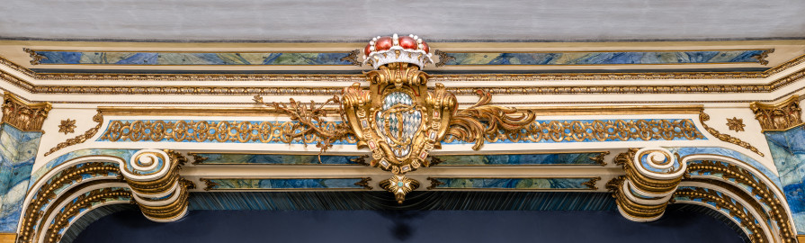 Schloss und Schlossgarten Schwetzingen - Garten - Schlosstheater - Von innen - Proszenium - Blick vom Parkett auf den Architravbalken des Proszeniums mit den beiden Volutenkonsolen; in der Mitte das kurfürstliche Wappen (mit dem Monogramm "CT" für Carl Theodor, dem Kurhut und einer Ordenskette) sowie Blatt- und Blütenranken (Gesamter Bau: Länge x Breite: ca. 62 x 35 Meter; Architekt: Nicolas de Pigage (1723-1796); Bauzeit: 1752-1753, Erweiterung 1762, Sanierung: 1937, Renovierung: 1952, Generalsanierung / Umbau 1971-1974, Restaurierung: 1999-2005) (aufgenommen im Dezember 2024, am Nachmittag) Schloss und Schlossgarten Schwetzingen - Garten - Schlosstheater - Von innen - Proszenium - Blick vom Parkett auf den Architravbalken des Proszeniums mit den beiden Volutenkonsolen; in der Mitte das kurfürstliche Wappen (mit dem Monogramm "CT" für Carl Theodor, dem Kurhut und einer Ordenskette) sowie Blatt- und Blütenranken (Gesamter Bau: Länge x Breite: ca. 62 x 35 Meter; Architekt: Nicolas de Pigage (1723-1796); Bauzeit: 1752-1753, Erweiterung 1762, Sanierung: 1937, Renovierung: 1952, Generalsanierung / Umbau 1971-1974, Restaurierung: 1999-2005) (aufgenommen im Dezember 2024, am Nachmittag)