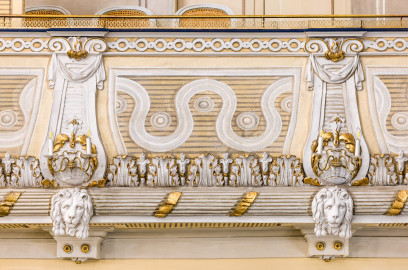 Schloss und Schlossgarten Schwetzingen - Garten - Schlosstheater - Von innen - Balkon - Von Norden - Blick vom Parkett auf die Brüstung der südwestlichsten Loge des Balkons mit reichen Verzierungen; unten ein kannelierter Rundstab, umwunden von einem vergoldeten Band, besetzt mit Löwenmasken, darüber ein Fries mit Akanthusblättern, darüber auf streifigem Grund ein Wellenband, dazwischen balusterartige Blenden mit Voluten, Tuchgehängen und Muscheln, darüber ein Fries aus Kreisen, darüber der Handlauf (Gesamter Bau: Länge x Breite: ca. 62 x 35 Meter; Architekt: Nicolas de Pigage (1723-1796); Bauzeit: 1752-1753, Erweiterung 1762, Sanierung: 1937, Renovierung: 1952, Generalsanierung / Umbau 1971-1974, Restaurierung: 1999-2005) (aufgenommen im Dezember 2024, am Nachmittag) Schloss und Schlossgarten Schwetzingen - Garten - Schlosstheater - Von innen - Balkon - Von Norden - Blick vom Parkett auf die Brüstung der südwestlichsten Loge des Balkons mit reichen Verzierungen; unten ein kannelierter Rundstab, umwunden von einem vergoldeten Band, besetzt mit Löwenmasken, darüber ein Fries mit Akanthusblättern, darüber auf streifigem Grund ein Wellenband, dazwischen balusterartige Blenden mit Voluten, Tuchgehängen und Muscheln, darüber ein Fries aus Kreisen, darüber der Handlauf (Gesamter Bau: Länge x Breite: ca. 62 x 35 Meter; Architekt: Nicolas de Pigage (1723-1796); Bauzeit: 1752-1753, Erweiterung 1762, Sanierung: 1937, Renovierung: 1952, Generalsanierung / Umbau 1971-1974, Restaurierung: 1999-2005) (aufgenommen im Dezember 2024, am Nachmittag)