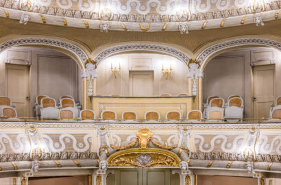 Schloss und Schlossgarten Schwetzingen - Garten - Schlosstheater - Von innen - Balkon, Mittelloge - Von Westen - Blick von der Bühne auf den östlichen Balkon (1. Rang) und die Mittelloge; die Stützen des Balkons geschmückt mit Faunsmasken, die Friese der Bogenkrümmungen des Balkons mit Rosetten besetzt; ganz unten der Haupteingang zum Parterre (Gesamter Bau: Länge x Breite: ca. 62 x 35 Meter; Architekt: Nicolas de Pigage (1723-1796); Bauzeit: 1752-1753, Erweiterung 1762, Sanierung: 1937, Renovierung: 1952, Generalsanierung / Umbau 1971-1974, Restaurierung: 1999-2005) (aufgenommen im Januar 2024, am frühen Nachmittag)