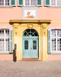 Schwetzingen - Schlossplatz, Nordseite - Palais Hirsch - Von außen - Von Süden - Portal mit Hauszeichen des Palais Hirsch (Architekt: Alessandro Galli da Bibiena (1686-1748), Baujahr: 1748, Standort: am damals neu angelegten Marktplatz; Renovierung/Umbau: 1970er Jahre; ursprünglich erbaut im Auftrag des Kurfürsten Carl Theodor für seinen Berater und Beichtvater, den Jesuitenpfarrer Franz Joseph Seedorf (1691-1758); ab 1818: Nutzung als „Gasthaus zum Goldenen Hirsch“; heute: städtisches Gebäude für repräsentative Zwecke, Veranstaltungsort für Konferenzen, Tagungen, Seminare und Empfänge, ebenso Sitz der Forschungsstelle Geschichte der Südwestdeutschen Hofmusik der Heidelberger Akademie der Wissenschaften sowie Ausstellungsort des Kunstvereins Schwetzingen) (aufgenommen im März 2025, am späten Vormittag) Schwetzingen - Schlossplatz, Nordseite - Palais Hirsch - Von außen - Von Süden - Portal mit Hauszeichen des Palais Hirsch (Architekt: Alessandro Galli da Bibiena (1686-1748), Baujahr: 1748, Standort: am damals neu angelegten Marktplatz; Renovierung/Umbau: 1970er Jahre; ursprünglich erbaut im Auftrag des Kurfürsten Carl Theodor für seinen Berater und Beichtvater, den Jesuitenpfarrer Franz Joseph Seedorf (1691-1758); ab 1818: Nutzung als „Gasthaus zum Goldenen Hirsch“; heute: städtisches Gebäude für repräsentative Zwecke, Veranstaltungsort für Konferenzen, Tagungen, Seminare und Empfänge, ebenso Sitz der Forschungsstelle Geschichte der Südwestdeutschen Hofmusik der Heidelberger Akademie der Wissenschaften sowie Ausstellungsort des Kunstvereins Schwetzingen) (aufgenommen im März 2025, am späten Vormittag)