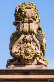 Schloss und Schlossgarten Schwetzingen - Schloss - Ehrenhof / Cour d'honneur - Eingangstor, linker / südlicher Torpfosten - Von Süden - Blick nach oben auf das Wappen von Kurfürst Johann Wilhelm (1658-1716, reg. 1690-1716); Bildhauer: Joseph Mauchert, Datierung: um 1713; ursprünglicher Aufstellungsort des Torpfostens mit dem Wappen: hinter der Brücke, um 1748 bei der Anlage des Marktplatzes vor der Brücke aufgestellt (aufgenommen im April 2025, am späten Vormittag)
