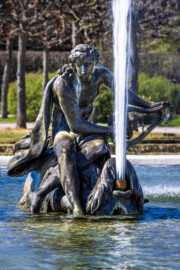 Schloss und Schlossgarten Schwetzingen - Garten - Kreisparterre - Arionbrunnen - Arion - Von Osten - Blick auf die die Skulptur "Arion auf einem Delfin" (Bildhauer: Barthélemy Guibal (1699-1757); Datierung: erste Hälfte 18. Jahrhundert; Material: Blei; geschaffen für die Sommerresidenz von Stanislaus I. Leszczyński (1677-1766) in Lunéville; gekauft 1766 von Carl Theodor (1724-1799, reg. 1742-1799)) (aufgenommen im April 2025, am Nachmittag)