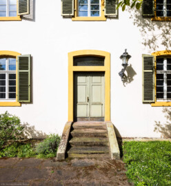 Schloss und Schlossgarten Schwetzingen - Sonstige Bauten - Altes Forstamt (Forsthausstraße 11) - Von Osten - Blick von der östlichen Gartenmauer nach Westen auf den Osteingang zum Forstamt (Bau: Länge x Breite: ca. 22 x 14 Meter; Geschosse: 2; Fensterachsen: 7; Bauzeit: 1760; erbaut als Haus des kurfürstlichen Oberjägermeisters; Verbindung mit dem Palais Ysenburg: 1775; Architekt: unbekannt) (aufgenommen im April 2025, am späten Vormittag)