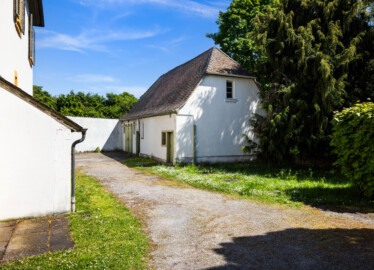 Schloss und Schlossgarten Schwetzingen - Sonstige Bauten - Altes Forstamt (Forsthausstraße 11) - Remise - Von Nordwest - Blick von der südwestlichen Ecke des Forstamts auf die Nordseite (links) und die Westseite (rechts) der Remise; ganz links der überdachte Kellereingang zum Forstamt (Bau: Länge x Breite: ca. 22 x 14 Meter; Geschosse: 2; Fensterachsen: 7; Bauzeit: 1760; erbaut als Haus des kurfürstlichen Oberjägermeisters; Verbindung mit dem Palais Ysenburg: 1775; Architekt: unbekannt) (aufgenommen im April 2025, am Nachmittag)