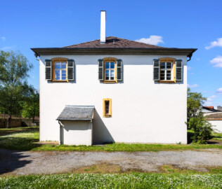Schloss und Schlossgarten Schwetzingen - Sonstige Bauten - Altes Forstamt (Forsthausstraße 11) - Von Süden - Blick vom Garten neben der Remise nach Norden auf die Südfassade des Forstamts mit dem überdachten Kellereingang (Bau: Länge x Breite: ca. 22 x 14 Meter; Geschosse: 2; Fensterachsen: 7; Bauzeit: 1760; erbaut als Haus des kurfürstlichen Oberjägermeisters; Verbindung mit dem Palais Ysenburg: 1775; Architekt: unbekannt) (aufgenommen im April 2025, am Nachmittag)