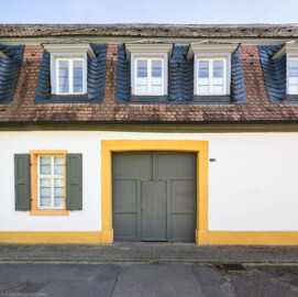 Schloss und Schlossgarten Schwetzingen - Sonstige Bauten - Palais Ysenburg (Forsthausstraße 7 und 9) - Von Norden - Blick auf das große Tor des Palais Ysenburg in der Forsthausstraße (ehemalige Bewohner: Mitglieder des kurfürstlichen Hofstaats, Oberhofgärter Theodor van Wynder († 1777), bis 1778 Oberstjägermeister Graf Friedrich Wilhelm von Ysenburg-Birstein (1730-1804) und Ehefrau Caroline Gräfin von Parkstein (1762-1816), eine uneheliche Tochter von Kurfürst Carl Theodor, Oberstjägermeister Johann Theodor Maria Reichsgraf v. Waldkirch (1720–1802), Oberforstmeister Friedrich Heinrich Georg Freiherr von Drais (1758-1833), ab 1864 der Industrielle Gustav Bassermann und Ehefrau Clementine; nach 1918 Kauf durch Stadt Schwetzingen, seit 1997 in Privatbesitz) (Bau: L-formig; Länge x Breite: Nordflügel ca. 34 x 7 Meter, Westflügel ca. 21 x 13 Meter, Westflügel mit Anbau bis zum Alten Forstamt ca. 48 x 10 Meter; Geschosse: 2 (inkl. Mansardgeschoss); Bauzeiten: 1760, Verbindung zum Alten Forstamt 1775, erweitert Ende des 19. Jh., restauriert 1997; Architekt: wohl Franz Wilhelm Rabaliatti (1714–1782)) (aufgenommen im April 2025, am Nachmittag) Schloss und Schlossgarten Schwetzingen - Sonstige Bauten - Palais Ysenburg (Forsthausstraße 7 und 9) - Von Norden - Blick auf das große Tor des Palais Ysenburg in der Forsthausstraße (ehemalige Bewohner: Mitglieder des kurfürstlichen Hofstaats, Oberhofgärter Theodor van Wynder († 1777), bis 1778 Oberstjägermeister Graf Friedrich Wilhelm von Ysenburg-Birstein (1730-1804) und Ehefrau Caroline Gräfin von Parkstein (1762-1816), eine uneheliche Tochter von Kurfürst Carl Theodor, Oberstjägermeister Johann Theodor Maria Reichsgraf v. Waldkirch (1720–1802), Oberforstmeister Friedrich Heinrich Georg Freiherr von Drais (1758-1833), ab 1864 der Industrielle Gustav Bassermann und Ehefrau Clementine; nach 1918 Kauf durch Stadt Schwetzingen, seit 1997 in Privatbesitz) (Bau: L-formig; Länge x Breite: Nordflügel ca. 34 x 7 Meter, Westflügel ca. 21 x 13 Meter, Westflügel mit Anbau bis zum Alten Forstamt ca. 48 x 10 Meter; Geschosse: 2 (inkl. Mansardgeschoss); Bauzeiten: 1760, Verbindung zum Alten Forstamt 1775, erweitert Ende des 19. Jh., restauriert 1997; Architekt: wohl Franz Wilhelm Rabaliatti (1714–1782)) (aufgenommen im April 2025, am Nachmittag)