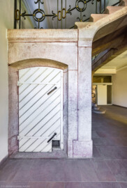 Schloss und Schlossgarten Schwetzingen - Sonstige Bauten - Altes Forstamt (Forsthausstraße 11) - Von innen - Treppenhaus - Erdgeschoss - Von Osten - Blick vom Fenster nach Westen auf die Tür zum Abgang in das Kellergeschoss; im Vordergrund ganz rechts der (nicht sichtbare) östliche Eingang; im Hintergrund ganz rechts der Durchgang in den westlichen Teil des Erdgeschosses (Bau: Länge x Breite: ca. 22 x 14 Meter; Geschosse: 2; Fensterachsen: 7; Bauzeit: 1760; erbaut als Haus des kurfürstlichen Oberjägermeisters; Verbindung mit dem Palais Ysenburg: 1775; Architekt: unbekannt) (aufgenommen im April 2025, am Nachmittag)