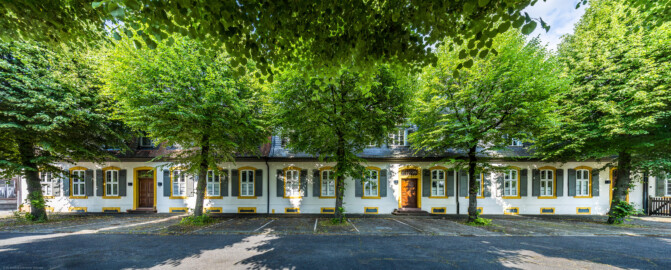 Schloss und Schlossgarten Schwetzingen - Sonstige Bauten - Palais Ysenburg (Forsthausstraße 7 und 9) - Von Nordwest - Blick von der Mauer zum Betriebshof in der Forsthausstraße nach Osten auf die Westseite des Palais Ysenburg (ehemalige Bewohner: Mitglieder des kurfürstlichen Hofstaats, Oberhofgärter Theodor van Wynder († 1777), bis 1778 Oberstjägermeister Graf Friedrich Wilhelm von Ysenburg-Birstein (1730-1804) und Ehefrau Caroline Gräfin von Parkstein (1762-1816), eine uneheliche Tochter von Kurfürst Carl Theodor, Oberstjägermeister Johann Theodor Maria Reichsgraf v. Waldkirch (1720–1802), Oberforstmeister Friedrich Heinrich Georg Freiherr von Drais (1758-1833), ab 1864 der Industrielle Gustav Bassermann und Ehefrau Clementine; nach 1918 Kauf durch Stadt Schwetzingen, seit 1997 in Privatbesitz) (Bau: L-formig; Länge x Breite: Nordflügel ca. 34 x 7 Meter, Westflügel ca. 21 x 13 Meter, Westflügel mit Anbau bis zum Alten Forstamt ca. 48 x 10 Meter; Geschosse: 2 (inkl. Mansardgeschoss); Bauzeiten: 1760, Verbindung zum Alten Forstamt 1775, erweitert Ende des 19. Jh., restauriert 1997; Architekt: wohl Franz Wilhelm Rabaliatti (1714–1782)) (aufgenommen im Juni 2025, am späten Nachmittag)