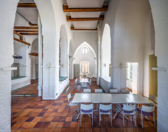 Schloss und Schlossgarten Schwetzingen - Sonstige Bauten - Oberes Wasserwerk - Wasserturm - Von innen - Obergeschoss / Cafeteria / Kantine - Von Westen - Blick vom südwestlichen Fenster nach Osten in den Raum; Wände und mittige Pfeiler sind "gotisch" bzw. spitzbogenartig gestaltet; links im Hintergrund eine kleine Zwischenebene zum Aufstieg in den Dachstuhl über Eisenleitern; links der Pfeiler und der rechten Wand vier Leitungen (Steigleitungen? / Fallleitungen?) von der Brunnenstube zu den Wasserbehältern im Dachgeschoss; eiserne Anker in den Pfeilern und Holzbalken dienten wohl als Zwischenebenen zur Lagerung (Gesamte Anlage Brunnenstube, Pumpenstube, Räderwerk, Wasserturm und Kühlhaus): Länge x Breite: ca. 30 x 29 Meter, Wasserturm: Länge x Breite: ca. 14 x 14 Meter, Firsthöhe ca. 24 Meter; Bauzeit Anlage: um 1774, Gesamtinstandsetzung: 1994–2000; Architekt: Nicolas de Pigage, Brunnenmeister: Thomas Breuer) (aufgenommen im Juni 2025, am späten Vormittag)
