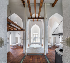 Schloss und Schlossgarten Schwetzingen - Sonstige Bauten - Oberes Wasserwerk - Wasserturm - Von innen - Obergeschoss / Cafeteria / Kantine - Von Norden - Zentraler Blick von der Tür zum Dachstuhl des sog. Reißbodens nach Süden in den Raum; Wände und mittige Pfeiler sind "gotisch" bzw. spitzbogenartig gestaltet; rechts die Theke der Cafeteria, links eine kleine Zwischenebene, die zum Dachstuhl über zwei Eisenleitern führt; rechts und links der mittleren Pfeiler vier Leitungen (Steigleitungen? / Fallleitungen?) von der Brunnenstube zu den Wasserbehältern im Dachgeschoss; eiserne Anker in den Wänden und Pfeilern und Holzbalken dienten wohl als Zwischenebenen zur Lagerung (Gesamte Anlage Brunnenstube, Pumpenstube, Räderwerk, Wasserturm und Kühlhaus): Länge x Breite: ca. 30 x 29 Meter, Wasserturm: Länge x Breite: ca. 14 x 14 Meter, Firsthöhe ca. 24 Meter; Bauzeit Anlage: um 1774, Gesamtinstandsetzung: 1994–2000; Architekt: Nicolas de Pigage, Brunnenmeister: Thomas Breuer) (aufgenommen im Juni 2025, um die Mittagszeit)