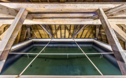 Schloss und Schlossgarten Schwetzingen - Sonstige Bauten - Oberes Wasserwerk - Wasserturm - Von innen - Dachstuhl - Von Osten - Zentraler Blick nach Westen von der Mitte des Laufstegs über das Wasserbecken in den Dachstuhl und das auf Wasserbecken; geschätzte Abmessungen des Behälters: Länge x Breite x Höhe 8 x 8 x 3 Meter, Fassungsvermögen ca. 170 Kubikmeter, Höhe über Boden ca. 17 Meter (Gesamte Anlage Brunnenstube, Pumpenstube, Räderwerk, Wasserturm und Kühlhaus): Länge x Breite: ca. 30 x 29 Meter, Wasserturm: Länge x Breite: ca. 14 x 14 Meter, Firsthöhe ca. 24 Meter; Bauzeit Anlage: um 1774, Gesamtinstandsetzung: 1994–2000; Architekt: Nicolas de Pigage, Brunnenmeister: Thomas Breuer) (aufgenommen im Juni 2025, am frühen Nachmittag)