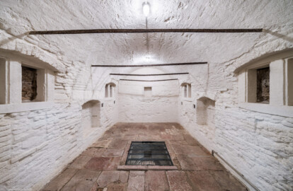 Schloss und Schlossgarten Schwetzingen - Sonstige Bauten - Oberes Wasserwerk - Kühlhaus - Von innen - Wildbretkeller - Von Süden - Blick vom Eingang zum Wildbretkeller nach Norden in den gewölbten Raum; der Wildbretkeller diente dem Abhängen von Wild an den eisernen Stangen und zur Lagerung von Lebensmitteln; am Fußboden in der Mitte ein großes Loch, um den darunter liegenden zugangslosen Eiskeller mit Eisblöcken zu befüllen (Gesamte Anlage Brunnenstube, Pumpenstube, Räderwerk, Wasserturm und Kühlhaus): Länge x Breite: ca. 30 x 29 Meter, Kühlhaus: Länge x Breite: ca. 14 x 13 Meter, Firsthöhe ca. 14 Meter, Kellertiefe ca. 3 Meter; Bauzeit Anlage: um 1774, Gesamtinstandsetzung: 1994–2000; Architekt: Nicolas de Pigage, Brunnenmeister: Thomas Breuer) (aufgenommen im Juni 2025, am Nachmittag)