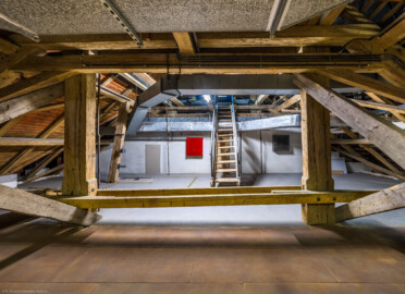 Schloss und Schlossgarten Schwetzingen - Garten - Schlosstheater - Von innen - Dachstuhl, über dem Zuschauerraum - Mittlere Ebene - Von Osten - Blick auf das westliche Ende des Dachstuhls über dem Zuschauerraum in der mittleren Ebene; hinter der weißen Mauer befindet sich der eiserne Vorhang; die Treppe führt zur oberen Ebene des Dachstuhls, die Falltür rechts des linken Balkens vor der Mauer führt über eine Treppe zur unteren Ebene des Dachstuhls (Gesamter Bau: Länge x Breite: ca. 62 x 35 Meter; Architekt: Nicolas de Pigage (1723-1796); Bauzeit: 1752-1753, Erweiterung 1762, Sanierung: 1937, Renovierung: 1952, Generalsanierung / Umbau 1971-1974, Restaurierung: 1999-2005) (aufgenommen im Juli 2025, am frühen Nachmittag) Schloss und Schlossgarten Schwetzingen - Garten - Schlosstheater - Von innen - Dachstuhl, über dem Zuschauerraum - Mittlere Ebene - Von Osten - Blick auf das westliche Ende des Dachstuhls über dem Zuschauerraum in der mittleren Ebene; hinter der weißen Mauer befindet sich der eiserne Vorhang; die Treppe führt zur oberen Ebene des Dachstuhls, die Falltür rechts des linken Balkens vor der Mauer führt über eine Treppe zur unteren Ebene des Dachstuhls (Gesamter Bau: Länge x Breite: ca. 62 x 35 Meter; Architekt: Nicolas de Pigage (1723-1796); Bauzeit: 1752-1753, Erweiterung 1762, Sanierung: 1937, Renovierung: 1952, Generalsanierung / Umbau 1971-1974, Restaurierung: 1999-2005) (aufgenommen im Juli 2025, am frühen Nachmittag)