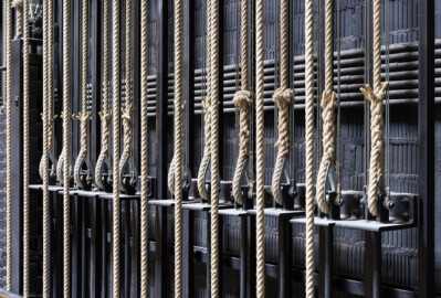 Schloss und Schlossgarten Schwetzingen - Garten - Schlosstheater - Von innen - Bühnenraum - Südliche Bühnenwand - Von Nordwest - Blick auf einige Handkonterzüge; die dicken Hanfseile sind die Kommandoseile, mit denen die Zugstangen (beladen z.B. mit Bühnenprospekt oder Scheinwerfern) in der Höhe verstellt werden können; das eine Ende eines Kommandoseils ist am Gegengewichtsschlitten (dem Winkel mit der Stange nach unten) befestigt; an diesem Schlitten sind auch die Stahlseile befestigt, die über Umlenkrollen die Last der Zugstange halten (Gesamter Bau: Länge x Breite: ca. 62 x 35 Meter; Architekt: Nicolas de Pigage (1723-1796); Bauzeit: 1752-1753, Erweiterung 1762, Sanierung: 1937, Renovierung: 1952, Generalsanierung / Umbau 1971-1974, Restaurierung: 1999-2005) (aufgenommen im Juli 2025, um die Mittagszeit) Schloss und Schlossgarten Schwetzingen - Garten - Schlosstheater - Von innen - Bühnenraum - Südliche Bühnenwand - Von Nordwest - Blick auf einige Handkonterzüge; die dicken Hanfseile sind die Kommandoseile, mit denen die Zugstangen (beladen z.B. mit Bühnenprospekt oder Scheinwerfern) in der Höhe verstellt werden können; das eine Ende eines Kommandoseils ist am Gegengewichtsschlitten (dem Winkel mit der Stange nach unten) befestigt; an diesem Schlitten sind auch die Stahlseile befestigt, die über Umlenkrollen die Last der Zugstange halten (Gesamter Bau: Länge x Breite: ca. 62 x 35 Meter; Architekt: Nicolas de Pigage (1723-1796); Bauzeit: 1752-1753, Erweiterung 1762, Sanierung: 1937, Renovierung: 1952, Generalsanierung / Umbau 1971-1974, Restaurierung: 1999-2005) (aufgenommen im Juli 2025, um die Mittagszeit)