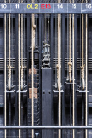 Schloss und Schlossgarten Schwetzingen - Garten - Schlosstheater - Von innen - Bühnenraum - Südliche Bühnenwand - Von Norden - Blick auf einige Handkonterzüge; die dicken Hanfseile sind die Kommandoseile, mit denen die Zugstangen (beladen z.B. mit Bühnenprospekt oder Scheinwerfern) in der Höhe verstellt werden können; das eine Ende eines Kommandoseils ist am Gegengewichtsschlitten (dem Winkel mit der Stange nach unten) befestigt; an diesem Schlitten sind auch die Stahlseile befestigt, die über Umlenkrollen die Last der Zugstange halten; in der Mitte ein Zug ("E13") mit elektromotorischem Antrieb (Gesamter Bau: Länge x Breite: ca. 62 x 35 Meter; Architekt: Nicolas de Pigage (1723-1796); Bauzeit: 1752-1753, Erweiterung 1762, Sanierung: 1937, Renovierung: 1952, Generalsanierung / Umbau 1971-1974, Restaurierung: 1999-2005) (aufgenommen im Juli 2025, am frühen Nachmittag) Schloss und Schlossgarten Schwetzingen - Garten - Schlosstheater - Von innen - Bühnenraum - Südliche Bühnenwand - Von Norden - Blick auf einige Handkonterzüge; die dicken Hanfseile sind die Kommandoseile, mit denen die Zugstangen (beladen z.B. mit Bühnenprospekt oder Scheinwerfern) in der Höhe verstellt werden können; das eine Ende eines Kommandoseils ist am Gegengewichtsschlitten (dem Winkel mit der Stange nach unten) befestigt; an diesem Schlitten sind auch die Stahlseile befestigt, die über Umlenkrollen die Last der Zugstange halten; in der Mitte ein Zug ("E13") mit elektromotorischem Antrieb (Gesamter Bau: Länge x Breite: ca. 62 x 35 Meter; Architekt: Nicolas de Pigage (1723-1796); Bauzeit: 1752-1753, Erweiterung 1762, Sanierung: 1937, Renovierung: 1952, Generalsanierung / Umbau 1971-1974, Restaurierung: 1999-2005) (aufgenommen im Juli 2025, am frühen Nachmittag)