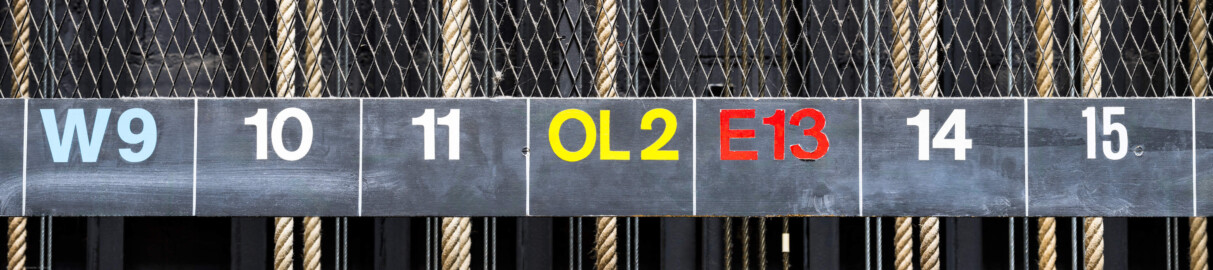 Schloss und Schlossgarten Schwetzingen - Garten - Schlosstheater - Von innen - Bühnenraum - Südliche Bühnenwand - Von Norden - Blick auf die breite Tafel mit den Bezeichnungen der ca. 55 Züge; Züge mit Zahlen sind Handkonterzüge (Nutzlast 200 kg), Züge "Po1" / "Po2" sind Portalzüge (150 kg), Züge "PaL" / "PaR" sind Panoramazüge (250 kg), Züge "OL2" / "OL3" / "OL4" sind Oberlichtzüge (250 kg), Züge beginnend mit "E" sind Elektro-Züge (500 kg, "E52" nur 150 kg), Züge beginnend mit "W" sind Elektro-Winden-Züge (500 kg) (Gesamter Bau: Länge x Breite: ca. 62 x 35 Meter; Architekt: Nicolas de Pigage (1723-1796); Bauzeit: 1752-1753, Erweiterung 1762, Sanierung: 1937, Renovierung: 1952, Generalsanierung / Umbau 1971-1974, Restaurierung: 1999-2005) (aufgenommen im Juli 2025, am Nachmittag) Schloss und Schlossgarten Schwetzingen - Garten - Schlosstheater - Von innen - Bühnenraum - Südliche Bühnenwand - Von Norden - Blick auf die breite Tafel mit den Bezeichnungen der ca. 55 Züge; Züge mit Zahlen sind Handkonterzüge (Nutzlast 200 kg), Züge "Po1" / "Po2" sind Portalzüge (150 kg), Züge "PaL" / "PaR" sind Panoramazüge (250 kg), Züge "OL2" / "OL3" / "OL4" sind Oberlichtzüge (250 kg), Züge beginnend mit "E" sind Elektro-Züge (500 kg, "E52" nur 150 kg), Züge beginnend mit "W" sind Elektro-Winden-Züge (500 kg) (Gesamter Bau: Länge x Breite: ca. 62 x 35 Meter; Architekt: Nicolas de Pigage (1723-1796); Bauzeit: 1752-1753, Erweiterung 1762, Sanierung: 1937, Renovierung: 1952, Generalsanierung / Umbau 1971-1974, Restaurierung: 1999-2005) (aufgenommen im Juli 2025, am Nachmittag)