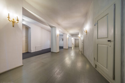 Schloss und Schlossgarten Schwetzingen - Garten - Schlosstheater - Von innen - Erdgeschoss, südliches Foyer - Von Osten - Blick vom Durchgang zum Foyer im Erdgeschoss nach Westen in das südliche Foyer; urprünglich befand sich die südliche Mauer des Theaters an der Stelle, an der heute die zwei Pfeiler stehen; beim großen Umbau 1971-1974 wurde das Schlosstheater zum nördlichen Zirkelbau (nach Süden / links) hin erweitert; originaler Bau und Anbau erkennbar am Boden: Holzboden bedeutet originaler Bau, Teppichboden bedeutet Anbau des 20. Jahrhunderts; rechts die Zugänge zu den Logen im Parterre; die große Tür links führt vom Foyer im nördlichen Zirkelbau in das südliche Foyer des Theaters; die Tür rechts der Bildmitte im Hintergrund führt zur Bühne, dem Orchestergraben und der Unterbühne (Gesamter Bau: Länge x Breite: ca. 62 x 35 Meter; Architekt: Nicolas de Pigage (1723-1796); Bauzeit: 1752-1753, Erweiterung 1762, Sanierung: 1937, Renovierung: 1952, Generalsanierung / Umbau 1971-1974, Restaurierung: 1999-2005) (aufgenommen im August 2025, am frühen Nachmittag)