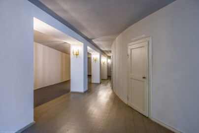 Schloss und Schlossgarten Schwetzingen - Garten - Schlosstheater - Von innen - 1. Obergeschoss (Balkon), südliches Foyer - Von Osten - Blick nach Westen in das südliche Foyer; rechts die Rückwand des hufeisenförmigen Zuschauerraums mit den Eingängen zum Balkon; urprünglich befand sich die südliche Mauer des Theaters an der Stelle, an der heute die drei Pfeiler stehen; beim großen Umbau 1971-1974 wurde das Schlosstheater zum nördlichen Zirkelbau (nach Süden / links) hin erweitert; originaler Bau und Anbau erkennbar am Boden: Holzboden bedeutet originaler Bau, Teppichboden bedeutet Anbau des 20. Jahrhunderts (Gesamter Bau: Länge x Breite: ca. 62 x 35 Meter; Architekt: Nicolas de Pigage (1723-1796); Bauzeit: 1752-1753, Erweiterung 1762, Sanierung: 1937, Renovierung: 1952, Generalsanierung / Umbau 1971-1974, Restaurierung: 1999-2005) (aufgenommen im August 2025, am späten Vormittag)
