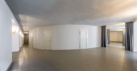 Schloss und Schlossgarten Schwetzingen - Garten - Schlosstheater - Von innen - 1. Obergeschoss (Balkon), südliches Foyer - Von Südost - Blick von der südöstlichen Ecke des Foyers nach Nordwest; in der Mitte die Rückwand des hufeisenförmigen Zuschauerraums mit den Eingängen zum Balkon; der östliche Eingang zum Balkon (rechts im Bild) kann auf drei Seiten mittels Vorhängen verschlossen werden; in diesem "Raum" kann ein Projektor und Steuerungstechnik aufgestellt werden, der für Bühnenprojektionen genutzt wird (z.B. zum Projezieren von Texten auf eine Fläche oberhalb des Bühnenportals) (Gesamter Bau: Länge x Breite: ca. 62 x 35 Meter; Architekt: Nicolas de Pigage (1723-1796); Bauzeit: 1752-1753, Erweiterung 1762, Sanierung: 1937, Renovierung: 1952, Generalsanierung / Umbau 1971-1974, Restaurierung: 1999-2005) (aufgenommen im August 2025, um die Mittagszeit)