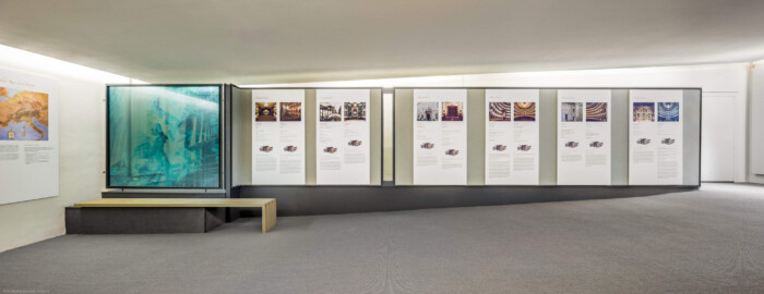 Schloss und Schlossgarten Schwetzingen - Garten - Schlosstheater - Von innen - 1. Obergeschoss (Balkon), nördliches Foyer - Von Süden - Blick nach Norden in das nördliche Foyer im 1. Obergeschoss; links und mittig Tafeln einer Ausstellung zu den Reisen Mozarts durch Europa sowie zu einigen Mozarttheatern (Gesamter Bau: Länge x Breite: ca. 62 x 35 Meter; Architekt: Nicolas de Pigage (1723-1796); Bauzeit: 1752-1753, Erweiterung 1762, Sanierung: 1937, Renovierung: 1952, Generalsanierung / Umbau 1971-1974, Restaurierung: 1999-2005) (aufgenommen im August 2025, am frühen Nachmittag)