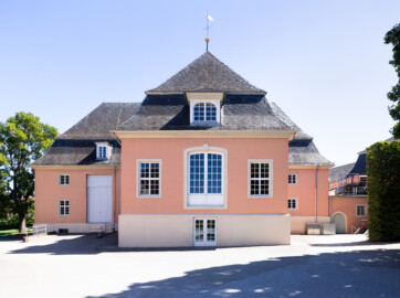 Schloss und Schlossgarten Schwetzingen - Garten - Schlosstheater - Von Nordwest - Blick von der Zufahrt zum Theater auf die Westfassade des Theaterbaus; hinter den drei mittleren Fenstern befindet sich die Hinterbühne, hinter dem großen Tor links die Seitenbühne; ganz rechts ein Zwischenbau zwischen dem Theater und dem Nördlichen Zirkelbau; ganz links befindet sich der Gesandtenhausgarten (Gesamter Bau: Länge x Breite: ca. 62 x 35 Meter; Architekt: Nicolas de Pigage (1723-1796); Bauzeit: 1752-1753, Erweiterung 1762, Sanierung: 1937, Renovierung: 1952, Generalsanierung / Umbau 1971-1974, Restaurierung: 1999-2005) (aufgenommen im August 2025, am Nachmittag)