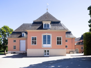 Schloss und Schlossgarten Schwetzingen - Garten - Schlosstheater - Von Nordwest - Blick von der Zufahrt zum Theater auf die Westfassade des Theaterbaus; hinter den drei mittleren Fenstern befindet sich die Hinterbühne, hinter dem großen Tor links die Seitenbühne; ganz rechts ein Zwischenbau zwischen dem Theater und dem Nördlichen Zirkelbau; ganz links befindet sich der Gesandtenhausgarten (Gesamter Bau: Länge x Breite: ca. 62 x 35 Meter; Architekt: Nicolas de Pigage (1723-1796); Bauzeit: 1752-1753, Erweiterung 1762, Sanierung: 1937, Renovierung: 1952, Generalsanierung / Umbau 1971-1974, Restaurierung: 1999-2005) (aufgenommen im August 2025, am Nachmittag) Schloss und Schlossgarten Schwetzingen - Garten - Schlosstheater - Von Nordwest - Blick von der Zufahrt zum Theater auf die Westfassade des Theaterbaus; hinter den drei mittleren Fenstern befindet sich die Hinterbühne, hinter dem großen Tor links die Seitenbühne; ganz rechts ein Zwischenbau zwischen dem Theater und dem Nördlichen Zirkelbau; ganz links befindet sich der Gesandtenhausgarten (Gesamter Bau: Länge x Breite: ca. 62 x 35 Meter; Architekt: Nicolas de Pigage (1723-1796); Bauzeit: 1752-1753, Erweiterung 1762, Sanierung: 1937, Renovierung: 1952, Generalsanierung / Umbau 1971-1974, Restaurierung: 1999-2005) (aufgenommen im August 2025, am Nachmittag)
