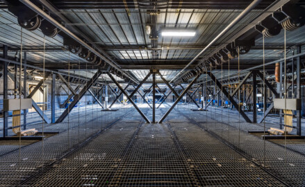 Schloss und Schlossgarten Schwetzingen - Garten - Schlosstheater - Von innen - Bühnenraum - Obermaschinerie - Rollenboden / Schnürboden - Von Westen - Zentraler Blick vom Eingang zum Rollenboden nach Osten auf den Schnürboden (Höhe ca. 13,5 Meter); der Rauchschieber (nicht sichtbar, links der Bildmitte, oberhalb der hellen Gitterfläche) auf dem Dach ist geöffnet, sodass Tageslicht auf den Rollenboden, die Gewichts- und Arbeitsgalerie unterhalb sowie auf die Bühne darunter fallen kann; jede der ca. 55 Zugstangen hängt an 4 Stahlseilen, die über Umlenkrollen (oben, je zwei links und zwei rechts) mit den Gewichtsschlitten an der Südwand des Bühnenraums verbunden sind; ganz rechts stehen die 12 Elektro- und Elektro-Winden-Züge (7 mit blauer Verkleidung, Nutzlast meist ca. 500 kg) (Gesamter Bau: Länge x Breite: ca. 62 x 35 Meter; Architekt: Nicolas de Pigage (1723-1796); Bauzeit: 1752-1753, Erweiterung 1762, Sanierung: 1937, Renovierung: 1952, Generalsanierung / Umbau 1971-1974, Restaurierung: 1999-2005) (aufgenommen im August 2025, am Nachmittag) Schloss und Schlossgarten Schwetzingen - Garten - Schlosstheater - Von innen - Bühnenraum - Obermaschinerie - Rollenboden / Schnürboden - Von Westen - Zentraler Blick vom Eingang zum Rollenboden nach Osten auf den Schnürboden (Höhe ca. 13,5 Meter); der Rauchschieber (nicht sichtbar, links der Bildmitte, oberhalb der hellen Gitterfläche) auf dem Dach ist geöffnet, sodass Tageslicht auf den Rollenboden, die Gewichts- und Arbeitsgalerie unterhalb sowie auf die Bühne darunter fallen kann; jede der ca. 55 Zugstangen hängt an 4 Stahlseilen, die über Umlenkrollen (oben, je zwei links und zwei rechts) mit den Gewichtsschlitten an der Südwand des Bühnenraums verbunden sind; ganz rechts stehen die 12 Elektro- und Elektro-Winden-Züge (7 mit blauer Verkleidung, Nutzlast meist ca. 500 kg) (Gesamter Bau: Länge x Breite: ca. 62 x 35 Meter; Architekt: Nicolas de Pigage (1723-1796); Bauzeit: 1752-1753, Erweiterung 1762, Sanierung: 1937, Renovierung: 1952, Generalsanierung / Umbau 1971-1974, Restaurierung: 1999-2005) (aufgenommen im August 2025, am Nachmittag)