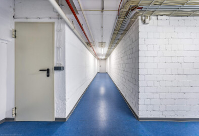 Schloss und Schlossgarten Schwetzingen - Garten - Schlosstheater - Von innen - Untergeschoss - Von Norden - Blick nach Süden in einen Gang des Untergeschosses; links die Tür zum hinteren Teil des Orchestergrabens, der unterhalb der Vorbühne liegt; in der Mitte die Tür zu einem Gang, der zur Unterbühne, zum Orchestergraben und zur Bühne führt; der Gang nach rechts führt zum Musiker-Aufenthaltsraum (Gesamter Bau: Länge x Breite: ca. 62 x 35 Meter; Architekt: Nicolas de Pigage (1723-1796); Bauzeit: 1752-1753, Erweiterung 1762, Sanierung: 1937, Renovierung: 1952, Generalsanierung / Umbau 1971-1974, Restaurierung: 1999-2005) (aufgenommen im September 2025, am späten Vormittag) Schloss und Schlossgarten Schwetzingen - Garten - Schlosstheater - Von innen - Untergeschoss - Von Norden - Blick nach Süden in einen Gang des Untergeschosses; links die Tür zum hinteren Teil des Orchestergrabens, der unterhalb der Vorbühne liegt; in der Mitte die Tür zu einem Gang, der zur Unterbühne, zum Orchestergraben und zur Bühne führt; der Gang nach rechts führt zum Musiker-Aufenthaltsraum (Gesamter Bau: Länge x Breite: ca. 62 x 35 Meter; Architekt: Nicolas de Pigage (1723-1796); Bauzeit: 1752-1753, Erweiterung 1762, Sanierung: 1937, Renovierung: 1952, Generalsanierung / Umbau 1971-1974, Restaurierung: 1999-2005) (aufgenommen im September 2025, am späten Vormittag)