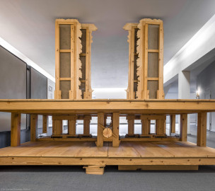 Schloss und Schlossgarten Schwetzingen - Garten - Schlosstheater - Von innen - 2. Obergeschoss (Rang), nördliches Foyer - Von Westen - Blick auf das Modell einer barocken Kulissenbühne aus Sicht der Hinterbühne; eine solche Kulissenbühne ist in Gassen eingeteilt, die von versetzt hintereinander angeordneten, meist bemalten Seitenkulissen gebildet werden; sie ermöglichen Auftritte von den Seiten und verbergen die Beleuchtung; die Seitenkulissen sind an vertikalen Hölzern befestigt, diese sind wiederum in der Unterbühne auf einem beweglichen horizontalen Schlitten, dem sog. Kulissenwagen, montiert; jeder Wagen ist mittels Schnurzügen mit einer zentralen Walze, dem sog. Wellenbaum, verbunden; dreht man den Wellenbaum, so können gleichzeitig mehrere Kulissenwagen verschoben werden; der Zuschauer sieht dadurch das gleichzeitige Erscheinen bzw. Verschwinden mehrerer Seitenkulissen (Gesamter Bau: Länge x Breite: ca. 62 x 35 Meter; Architekt: Nicolas de Pigage (1723-1796); Bauzeit: 1752-1753, Erweiterung 1762, Sanierung: 1937, Renovierung: 1952, Generalsanierung / Umbau 1971-1974, Restaurierung: 1999-2005) (aufgenommen im September 2025, am frühen Nachmittag) Schloss und Schlossgarten Schwetzingen - Garten - Schlosstheater - Von innen - 2. Obergeschoss (Rang), nördliches Foyer - Von Westen - Blick auf das Modell einer barocken Kulissenbühne aus Sicht der Hinterbühne; eine solche Kulissenbühne ist in Gassen eingeteilt, die von versetzt hintereinander angeordneten, meist bemalten Seitenkulissen gebildet werden; sie ermöglichen Auftritte von den Seiten und verbergen die Beleuchtung; die Seitenkulissen sind an vertikalen Hölzern befestigt, diese sind wiederum in der Unterbühne auf einem beweglichen horizontalen Schlitten, dem sog. Kulissenwagen, montiert; jeder Wagen ist mittels Schnurzügen mit einer zentralen Walze, dem sog. Wellenbaum, verbunden; dreht man den Wellenbaum, so können gleichzeitig mehrere Kulissenwagen verschoben werden; der Zuschauer sieht dadurch das gleichzeitige Erscheinen bzw. Verschwinden mehrerer Seitenkulissen (Gesamter Bau: Länge x Breite: ca. 62 x 35 Meter; Architekt: Nicolas de Pigage (1723-1796); Bauzeit: 1752-1753, Erweiterung 1762, Sanierung: 1937, Renovierung: 1952, Generalsanierung / Umbau 1971-1974, Restaurierung: 1999-2005) (aufgenommen im September 2025, am frühen Nachmittag)