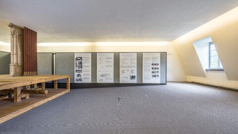Schloss und Schlossgarten Schwetzingen - Garten - Schlosstheater - Von innen - 2. Obergeschoss (Rang), nördliches Foyer - Von Süden - Blick nach Norden in das nördliche Foyer im 2. Obergeschoss; links das Modell einer barocken Kulissenbühne (mit verschiebbaren Kulissen); rechts Tafeln zur barocken Bühnenmaschinerie sowie zur Bauaufnahme und Bauforschung in Schwetzingen (Gesamter Bau: Länge x Breite: ca. 62 x 35 Meter; Architekt: Nicolas de Pigage (1723-1796); Bauzeit: 1752-1753, Erweiterung 1762, Sanierung: 1937, Renovierung: 1952, Generalsanierung / Umbau 1971-1974, Restaurierung: 1999-2005) (aufgenommen im September 2025, am Nachmittag)