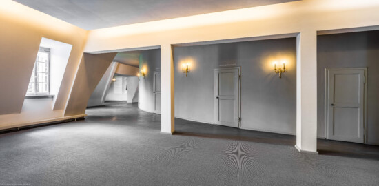 Schloss und Schlossgarten Schwetzingen - Garten - Schlosstheater - Von innen - 2. Obergeschoss (Rang), nördliches Foyer - Von Nordwest - Blick nach Südost in das nördliche und (links im Hintergrund) das östliche Foyer im 2. Obergeschoss; urprünglich befand sich die nördliche Mauer des Theaters an der Stelle, an der heute die drei Pfeiler stehen; in den 1950/1960er Jahren und vor allem beim großen Umbau 1971-1974 wurde das Schlosstheater nach Norden hin erweitert; originaler Bau und Anbau erkennbar am Boden: Holzboden bedeutet originaler Bau, Teppichboden bedeutet Anbau des 20. Jahrhunderts; mittig und rechts die Zugänge zum Rang (Gesamter Bau: Länge x Breite: ca. 62 x 35 Meter; Architekt: Nicolas de Pigage (1723-1796); Bauzeit: 1752-1753, Erweiterung 1762, Sanierung: 1937, Renovierung: 1952, Generalsanierung / Umbau 1971-1974, Restaurierung: 1999-2005) (aufgenommen im September 2025, am frühen Nachmittag)