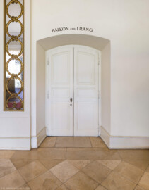 Schloss und Schlossgarten Schwetzingen - Garten - Nördlicher Zirkelbau - Westlicher Pavillon / Foyer des Schlosstheaters - Von innen - Nordwand, Mitte - Von Südwest - Blick auf die Eingangstür zum südöstlichen Treppenhaus zum 1. Obergeschoss (Balkon) und zum 2. Obergeschoss (Rang); durch diese Tür gelangt man nicht in das Foyer im Erdgeschoss  (Gesamter Bau: Länge Bogen ca. 175 Meter, Breite zwischen ca. 11 und 18 Meter, 51 Achsen, 5 Pavillons, 4 Zwischenbauten; Architekt: Alessandro Alessandro Galli da Bibiena (1686-1748), Bauleitung: zuerst Guillaume d’Hauberat (1680–1749), dann Nicolas de Pigage (1723-1796); Bauzeit: 1748-1750) (aufgenommen im September 2025, am späten Vormittag)