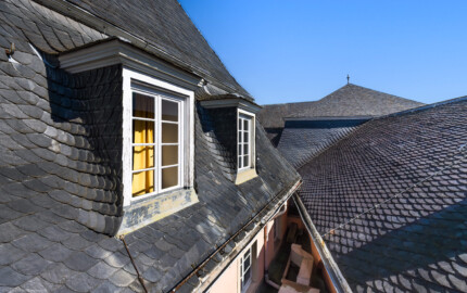 Schloss und Schlossgarten Schwetzingen - Garten - Schlosstheater - Von aussen - Dächer / Dachzerfallung - Von Westen - Blick von der Plattform des Notausstiegsfensters im großen Umkleideraum auf der Südseite des 2. Obergeschosses nach Osten auf eine komplexe Dachzerfallung: links das südliche Dach des Theaters mit zwei Dachgauben, rechts das Dach des westlichen Zwischenbaus (Schlossrestaurant) des Nördlichen Zirkelbaus, vorne rechts das Dach des westlichen Pavillons (Theaterfoyer) des Nördlichen Zirkelbaus und hinten etwas rechts oberhalb der Bildmitte das Dach des Verbindungsbaus zwischen dem westlichen Pavillon (Theaterfoyer) und dem Theater (Gesamter Bau: Länge x Breite: ca. 62 x 35 Meter; Architekt: Nicolas de Pigage (1723-1796); Bauzeit: 1752-1753, Erweiterung 1762, Sanierung: 1937, Renovierung: 1952, Generalsanierung / Umbau 1971-1974, Restaurierung: 1999-2005) (aufgenommen im September 2025, am Nachmittag)