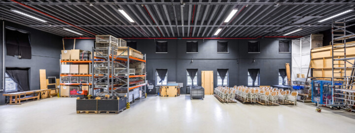 Schloss und Schlossgarten Schwetzingen - Garten - Schlosstheater - Von innen - Bühnenraum - Seitenbühne - Von Süden - Zentraler Blick vom geschlossenen Seitenbühnentor nach Norden in die (für die Zuschauer nicht einsehbare) Seitenbühne; die Seitenbühne dient als (Zwischen-) Lager für Bühnenbilder, Requisiten und Bühnentechnik, dem schnellen Kulissen- bzw. Szenenechsel sowie den Schauspielern zum Betreten und Verlassen der Bühne; an der Nordwand (im Hintergrund) die sieben Fenster in zwei Reihen zum Gesandtenhausgarten hin; die Stühle auf der rechten Seite können bei einer Schauspiel-Bestuhlung auf dem Boden des Proszeniums montiert werden; (Gesamter Bau: Länge x Breite: ca. 62 x 35 Meter; Architekt: Nicolas de Pigage (1723-1796); Bauzeit: 1752-1753, Erweiterung 1762, Sanierung: 1937, Renovierung: 1952, Generalsanierung / Umbau 1971-1974, Restaurierung: 1999-2005) (aufgenommen im September 2025, am Nachmittag) Schloss und Schlossgarten Schwetzingen - Garten - Schlosstheater - Von innen - Bühnenraum - Seitenbühne - Von Süden - Zentraler Blick vom geschlossenen Seitenbühnentor nach Norden in die (für die Zuschauer nicht einsehbare) Seitenbühne; die Seitenbühne dient als (Zwischen-) Lager für Bühnenbilder, Requisiten und Bühnentechnik, dem schnellen Kulissen- bzw. Szenenechsel sowie den Schauspielern zum Betreten und Verlassen der Bühne; an der Nordwand (im Hintergrund) die sieben Fenster in zwei Reihen zum Gesandtenhausgarten hin; die Stühle auf der rechten Seite können bei einer Schauspiel-Bestuhlung auf dem Boden des Proszeniums montiert werden; (Gesamter Bau: Länge x Breite: ca. 62 x 35 Meter; Architekt: Nicolas de Pigage (1723-1796); Bauzeit: 1752-1753, Erweiterung 1762, Sanierung: 1937, Renovierung: 1952, Generalsanierung / Umbau 1971-1974, Restaurierung: 1999-2005) (aufgenommen im September 2025, am Nachmittag)