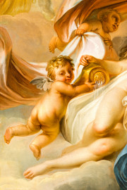 Schloss und Schlossgarten Schwetzingen - Garten - Badhaus - Von innen - Ovalsaal - Deckengemälde - Von unten - Ausschnitt aus dem Deckengemälde "Aurora vertreibt die Nacht": Putto links der Tauschwestern (Maler: Nicolas Guibal (1725-1784); Datierung: 1772; Signaturen: links unten "N. Guibal Lotharingus inv et fecit 1772" und rechts unten "N. Guibal Lotharingus invenit et pinxit 1772"; Öl auf Leinwand, mit vergoldeten Eichenlaubkranz eingefasst; Restaurierungen: 1890, 1949, 2006) (Gesamter Bau: Länge x Breite ca. 18 x 14 Meter, Höhe ca. 10 Meter; Architekt: Nicolas de Pigage (1723-1796); Bauzeit: 1768-1772; Gesamtinstandsetzung innen und außen: 1999-2006) (aufgenommen im Oktober 2025, am Nachmittag) Schloss und Schlossgarten Schwetzingen - Garten - Badhaus - Von innen - Ovalsaal - Deckengemälde - Von unten - Ausschnitt aus dem Deckengemälde "Aurora vertreibt die Nacht": Putto links der Tauschwestern (Maler: Nicolas Guibal (1725-1784); Datierung: 1772; Signaturen: links unten "N. Guibal Lotharingus inv et fecit 1772" und rechts unten "N. Guibal Lotharingus invenit et pinxit 1772"; Öl auf Leinwand, mit vergoldeten Eichenlaubkranz eingefasst; Restaurierungen: 1890, 1949, 2006) (Gesamter Bau: Länge x Breite ca. 18 x 14 Meter, Höhe ca. 10 Meter; Architekt: Nicolas de Pigage (1723-1796); Bauzeit: 1768-1772; Gesamtinstandsetzung innen und außen: 1999-2006) (aufgenommen im Oktober 2025, am Nachmittag)
