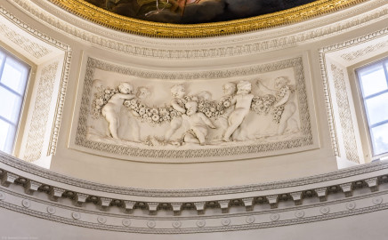 Schloss und Schlossgarten Schwetzingen - Garten - Badhaus - Von innen - Ovalsaal - Puttenfriese - Von Nordwest - Südöstliches Feld im Tambour: neun spielende Putti, verbunden durch eine Blumen- und Fruchtgirlande, eingebettet in ein Feld mit Tropfenstuck, umgeben von einem glatten Rahmen (Stuckateur: Giuseppe Antonio Pozzi (1732–1811)) (Gesamter Bau: Länge x Breite ca. 18 x 14 Meter, Höhe ca. 10 Meter; Architekt: Nicolas de Pigage (1723-1796); Bauzeit: 1768-1772; Gesamtinstandsetzung innen und außen: 1999-2006) (aufgenommen im Oktober 2025, am frühen Nachmittag) Schloss und Schlossgarten Schwetzingen - Garten - Badhaus - Von innen - Ovalsaal - Puttenfriese - Von Nordwest - Südöstliches Feld im Tambour: neun spielende Putti, verbunden durch eine Blumen- und Fruchtgirlande, eingebettet in ein Feld mit Tropfenstuck, umgeben von einem glatten Rahmen (Stuckateur: Giuseppe Antonio Pozzi (1732–1811)) (Gesamter Bau: Länge x Breite ca. 18 x 14 Meter, Höhe ca. 10 Meter; Architekt: Nicolas de Pigage (1723-1796); Bauzeit: 1768-1772; Gesamtinstandsetzung innen und außen: 1999-2006) (aufgenommen im Oktober 2025, am frühen Nachmittag)