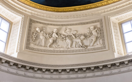 Schloss und Schlossgarten Schwetzingen - Garten - Badhaus - Von innen - Ovalsaal - Puttenfriese - Von Südost - Nordwestliches Feld im Tambour: acht spielende Putti, verbunden durch eine Blumen- und Fruchtgirlande, eingebettet in ein Feld mit Tropfenstuck, umgeben von einem glatten Rahmen (Stuckateur: Giuseppe Antonio Pozzi (1732–1811)) (Gesamter Bau: Länge x Breite ca. 18 x 14 Meter, Höhe ca. 10 Meter; Architekt: Nicolas de Pigage (1723-1796); Bauzeit: 1768-1772; Gesamtinstandsetzung innen und außen: 1999-2006) (aufgenommen im Oktober 2025, am frühen Nachmittag) Schloss und Schlossgarten Schwetzingen - Garten - Badhaus - Von innen - Ovalsaal - Puttenfriese - Von Südost - Nordwestliches Feld im Tambour: acht spielende Putti, verbunden durch eine Blumen- und Fruchtgirlande, eingebettet in ein Feld mit Tropfenstuck, umgeben von einem glatten Rahmen (Stuckateur: Giuseppe Antonio Pozzi (1732–1811)) (Gesamter Bau: Länge x Breite ca. 18 x 14 Meter, Höhe ca. 10 Meter; Architekt: Nicolas de Pigage (1723-1796); Bauzeit: 1768-1772; Gesamtinstandsetzung innen und außen: 1999-2006) (aufgenommen im Oktober 2025, am frühen Nachmittag)