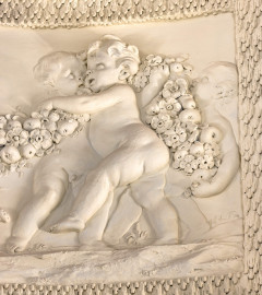 Schloss und Schlossgarten Schwetzingen - Garten - Badhaus - Von innen - Ovalsaal - Puttenfriese - Von Nordost - Ausschnitt aus dem südwestliches Feld im Tambour: spielende Putti, verbunden durch eine Blumen- und Fruchtgirlande (Stuckateur: Giuseppe Antonio Pozzi (1732–1811)) (Gesamter Bau: Länge x Breite ca. 18 x 14 Meter, Höhe ca. 10 Meter; Architekt: Nicolas de Pigage (1723-1796); Bauzeit: 1768-1772; Gesamtinstandsetzung innen und außen: 1999-2006) (aufgenommen im Oktober 2025, am frühen Nachmittag) Schloss und Schlossgarten Schwetzingen - Garten - Badhaus - Von innen - Ovalsaal - Puttenfriese - Von Nordost - Ausschnitt aus dem südwestliches Feld im Tambour: spielende Putti, verbunden durch eine Blumen- und Fruchtgirlande (Stuckateur: Giuseppe Antonio Pozzi (1732–1811)) (Gesamter Bau: Länge x Breite ca. 18 x 14 Meter, Höhe ca. 10 Meter; Architekt: Nicolas de Pigage (1723-1796); Bauzeit: 1768-1772; Gesamtinstandsetzung innen und außen: 1999-2006) (aufgenommen im Oktober 2025, am frühen Nachmittag)