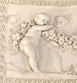 Schloss und Schlossgarten Schwetzingen - Garten - Badhaus - Von innen - Ovalsaal - Puttenfriese - Von Nordwest - Ausschnitt aus dem südöstliches Feld im Tambour: spielende Putti, verbunden durch eine Blumen- und Fruchtgirlande (Stuckateur: Giuseppe Antonio Pozzi (1732–1811)) (Gesamter Bau: Länge x Breite ca. 18 x 14 Meter, Höhe ca. 10 Meter; Architekt: Nicolas de Pigage (1723-1796); Bauzeit: 1768-1772; Gesamtinstandsetzung innen und außen: 1999-2006) (aufgenommen im Oktober 2025, am frühen Nachmittag) Schloss und Schlossgarten Schwetzingen - Garten - Badhaus - Von innen - Ovalsaal - Puttenfriese - Von Nordwest - Ausschnitt aus dem südöstliches Feld im Tambour: spielende Putti, verbunden durch eine Blumen- und Fruchtgirlande (Stuckateur: Giuseppe Antonio Pozzi (1732–1811)) (Gesamter Bau: Länge x Breite ca. 18 x 14 Meter, Höhe ca. 10 Meter; Architekt: Nicolas de Pigage (1723-1796); Bauzeit: 1768-1772; Gesamtinstandsetzung innen und außen: 1999-2006) (aufgenommen im Oktober 2025, am frühen Nachmittag)