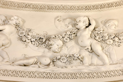 Schloss und Schlossgarten Schwetzingen - Garten - Badhaus - Von innen - Ovalsaal - Puttenfriese - Von Südwest - Ausschnitt aus dem nordöstliches Feld im Tambour: spielende Putti, verbunden durch eine Blumen- und Fruchtgirlande (Stuckateur: Giuseppe Antonio Pozzi (1732–1811)) (Gesamter Bau: Länge x Breite ca. 18 x 14 Meter, Höhe ca. 10 Meter; Architekt: Nicolas de Pigage (1723-1796); Bauzeit: 1768-1772; Gesamtinstandsetzung innen und außen: 1999-2006) (aufgenommen im Oktober 2025, am frühen Nachmittag) Schloss und Schlossgarten Schwetzingen - Garten - Badhaus - Von innen - Ovalsaal - Puttenfriese - Von Südwest - Ausschnitt aus dem nordöstliches Feld im Tambour: spielende Putti, verbunden durch eine Blumen- und Fruchtgirlande (Stuckateur: Giuseppe Antonio Pozzi (1732–1811)) (Gesamter Bau: Länge x Breite ca. 18 x 14 Meter, Höhe ca. 10 Meter; Architekt: Nicolas de Pigage (1723-1796); Bauzeit: 1768-1772; Gesamtinstandsetzung innen und außen: 1999-2006) (aufgenommen im Oktober 2025, am frühen Nachmittag)