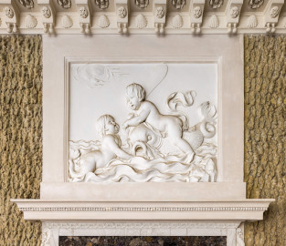 Schloss und Schlossgarten Schwetzingen - Garten - Badhaus - Von innen - Baderaum - Supraporte, Südseite - Von Norden - Blick auf die Supraporte über der (südlichen) Eingangstür; Putti mit Wasserattributen in Reliefdarstellung, umgeben von einem glatten Rahmen; ein Putto reitet einen Delphin und hält ein Paddel in der Hand, ein zweiter Putto schwimmt in stark bewegten Wellen; Gesims der Türeinfassung aus Stuck geschmückt mit Perlstab und Blattfries; in der Kehle der Decke Stuckkonsolen mit birnenförmigen Tropfen, Muscheln, Blütenrosetten (Stuckateur: Giuseppe Antonio Pozzi (1732–1811)) (Gesamter Bau: Länge x Breite ca. 18 x 14 Meter, Höhe ca. 10 Meter; Architekt: Nicolas de Pigage (1723-1796); Bauzeit: 1768-1772; Gesamtinstandsetzung innen und außen: 1999-2006) (aufgenommen im Oktober 2025, am Nachmittag) Schloss und Schlossgarten Schwetzingen - Garten - Badhaus - Von innen - Baderaum - Supraporte, Südseite - Von Norden - Blick auf die Supraporte über der (südlichen) Eingangstür; Putti mit Wasserattributen in Reliefdarstellung, umgeben von einem glatten Rahmen; ein Putto reitet einen Delphin und hält ein Paddel in der Hand, ein zweiter Putto schwimmt in stark bewegten Wellen; Gesims der Türeinfassung aus Stuck geschmückt mit Perlstab und Blattfries; in der Kehle der Decke Stuckkonsolen mit birnenförmigen Tropfen, Muscheln, Blütenrosetten (Stuckateur: Giuseppe Antonio Pozzi (1732–1811)) (Gesamter Bau: Länge x Breite ca. 18 x 14 Meter, Höhe ca. 10 Meter; Architekt: Nicolas de Pigage (1723-1796); Bauzeit: 1768-1772; Gesamtinstandsetzung innen und außen: 1999-2006) (aufgenommen im Oktober 2025, am Nachmittag)