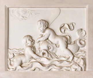 Schloss und Schlossgarten Schwetzingen - Garten - Badhaus - Von innen - Baderaum - Supraporte, Südseite - Von Norden - Putti mit Wasserattributen in Reliefdarstellung; ein Putto reitet einen Delphin und hält ein Paddel in der Hand, ein zweiter Putto schwimmt in stark bewegten Wellen (Stuckateur: Giuseppe Antonio Pozzi (1732–1811)) (Gesamter Bau: Länge x Breite ca. 18 x 14 Meter, Höhe ca. 10 Meter; Architekt: Nicolas de Pigage (1723-1796); Bauzeit: 1768-1772; Gesamtinstandsetzung innen und außen: 1999-2006) (aufgenommen im Oktober 2025, am Nachmittag)