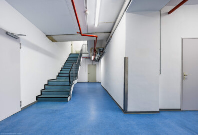 Schloss und Schlossgarten Schwetzingen - Garten - Schlosstheater - Von innen - Westliches Treppenhaus - Untergeschoss - Von Norden - Blick vom östlichen Ende des Mittelgangs im Untergeschoss nach Süden; links die Tür zur Unterbühne, rechts der Gang zum zentralen westlichen Eingang zum Theater, mittig die Tür zu den Garderoben; die Treppe führt nach oben in das Erdgeschoss; links der Treppe oben der südwestliche Zugang zur Bühne (Gesamter Bau: Länge x Breite: ca. 62 x 35 Meter; Architekt: Nicolas de Pigage (1723-1796); Bauzeit: 1752-1753, Erweiterung 1762, Sanierung: 1937, Renovierung: 1952, Generalsanierung / Umbau 1971-1974, Restaurierung: 1999-2005) (aufgenommen im Oktober 2025, um die Mittagszeit) Schloss und Schlossgarten Schwetzingen - Garten - Schlosstheater - Von innen - Westliches Treppenhaus - Untergeschoss - Von Norden - Blick vom östlichen Ende des Mittelgangs im Untergeschoss nach Süden; links die Tür zur Unterbühne, rechts der Gang zum zentralen westlichen Eingang zum Theater, mittig die Tür zu den Garderoben; die Treppe führt nach oben in das Erdgeschoss; links der Treppe oben der südwestliche Zugang zur Bühne (Gesamter Bau: Länge x Breite: ca. 62 x 35 Meter; Architekt: Nicolas de Pigage (1723-1796); Bauzeit: 1752-1753, Erweiterung 1762, Sanierung: 1937, Renovierung: 1952, Generalsanierung / Umbau 1971-1974, Restaurierung: 1999-2005) (aufgenommen im Oktober 2025, um die Mittagszeit)